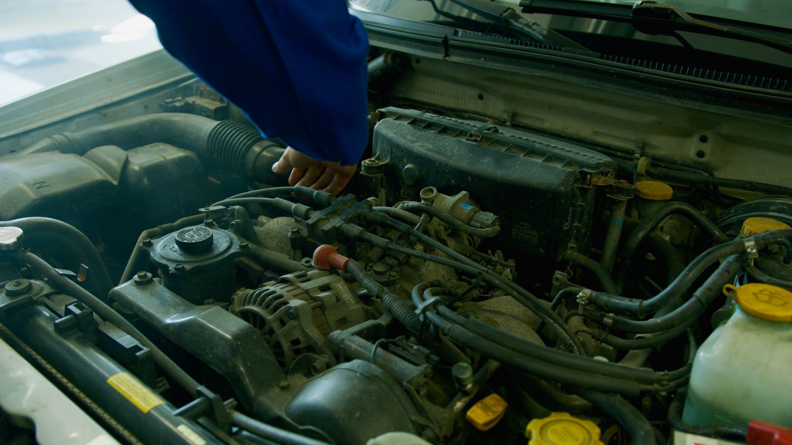Mecanic lucrând la motorul unei mașini